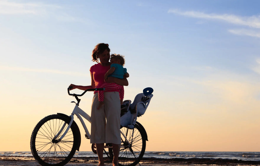 Moeder en baby fiets ondergaande zon