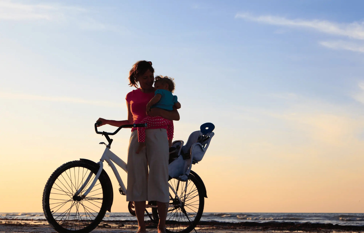 Moeder en baby fiets ondergaande zon